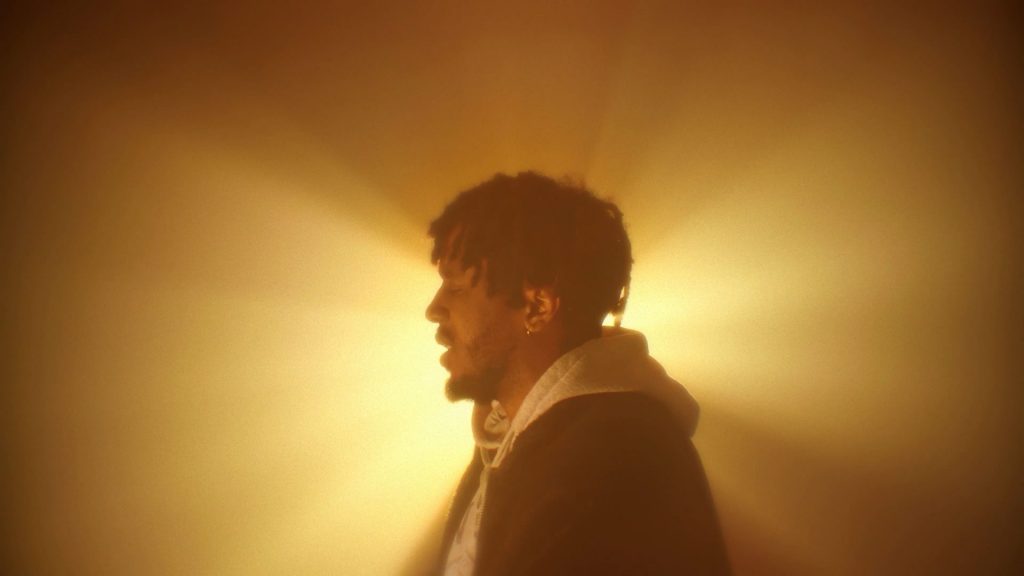 Baboune artiste rap bordelais en contre jour derrière une lumière doré